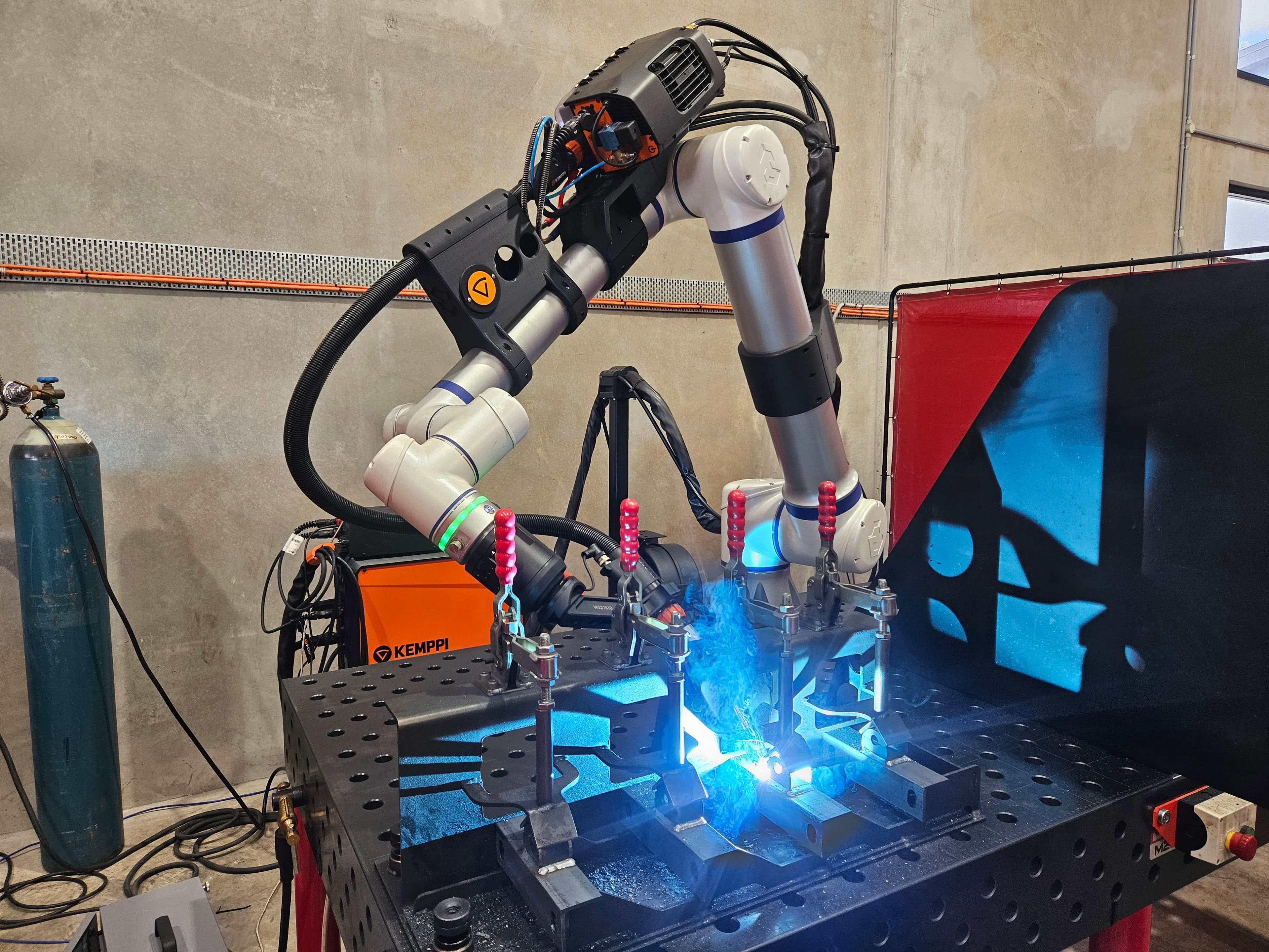 Cobot welder with Kemppi orange power supply visible